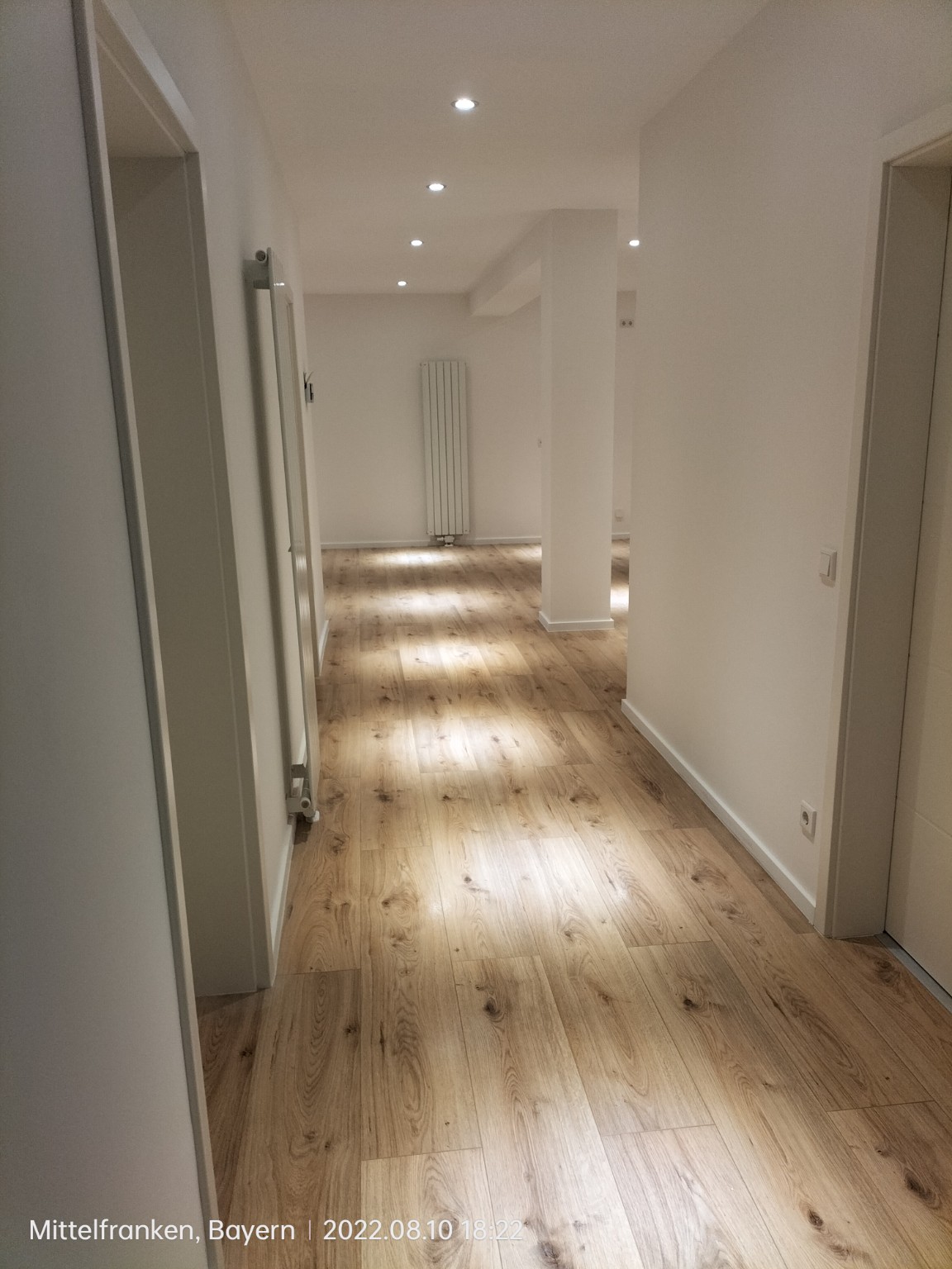 Corredor en Fürth con suelo de acabado madera, rodapiés blancos y puertas instaladas
