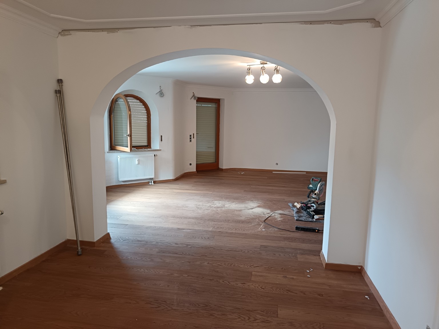 Suelo de acabado madera y rodapiés en salón con arco, durante la obra