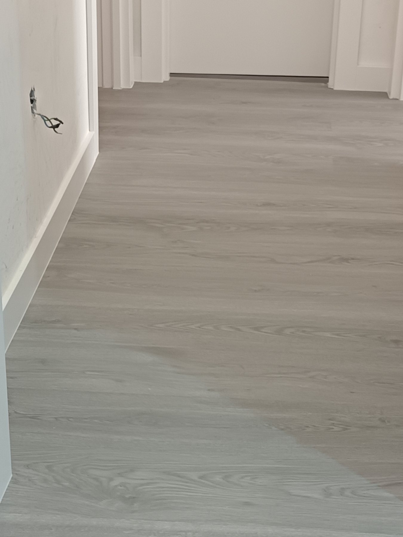 Pasillo con suelo laminado gris y rodapiés blancos en Zamora