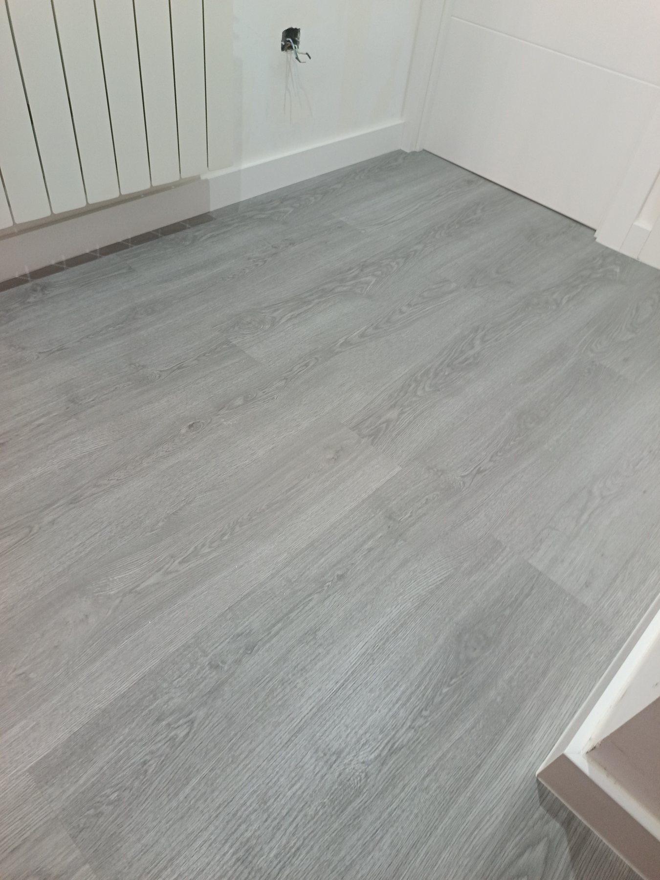 Detalle del suelo laminado terminado junto a radiador y paredes blancas en Zamora