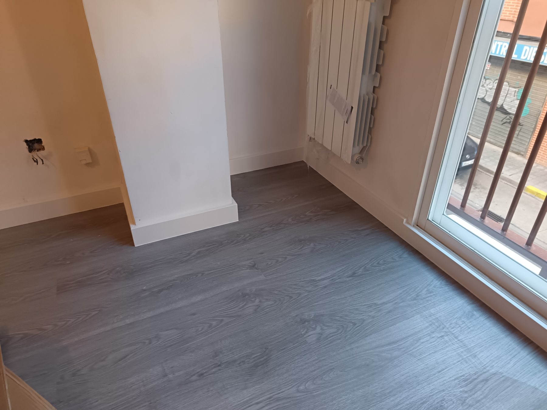 Detalle de suelo laminado junto a ventana y radiador en una obra de Zamora